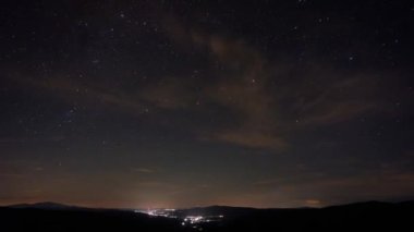 Gece gökyüzü yıldızlarla hızlı hareket eden bulutlar geceden şafağa, uzak bir şehrin gece ışıkları