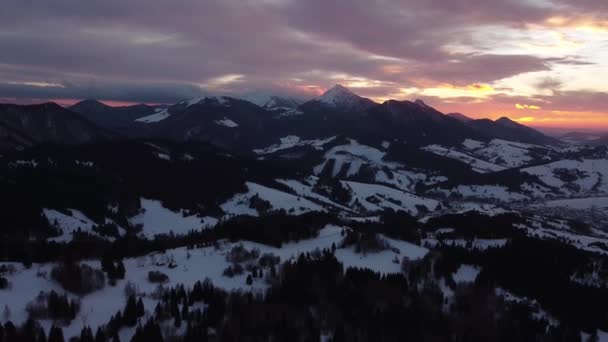 Вид с воздуха на закат над зимней горой, пейзаж деревьев, цветные облака в сумерках. 4K-видео. — стоковое видео