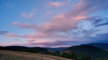 Gün batımında renkli bulutlar Karpat tepelerindeki tepe ve orman manzarasının üzerinde