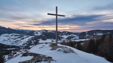 Gün batımında Karlı bir arazide Rocky Hill 'de haç