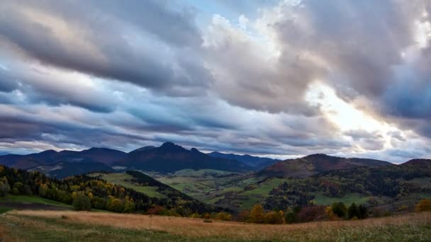 Αγροτικό ορεινό τοπίο το σούρουπο Πυκνά σύννεφα στο ηλιοβασιλέμα.Αφήνει στα δέντρα χρωματισμένα σε φθινοπωρινά χρώματα — Αρχείο Βίντεο