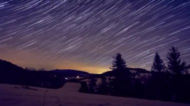 Ormanda kış manzarasında yıldızlı gece gökyüzü. Kayan yıldızlar, yıldızlar, uzun kuyruklar, meteorlar.