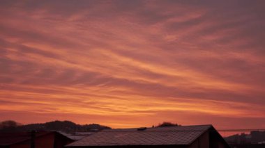 Gün doğumunda evlerin çatısında hareket eden bulutların zamanı.
