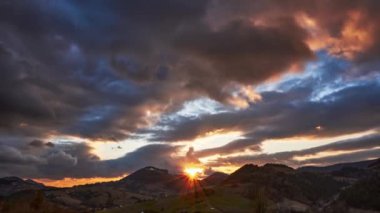 Gün batımı, yoğun renkli bulutlar, hızlı hareket eden bulutlar. Hilly kırsal bahar manzarası