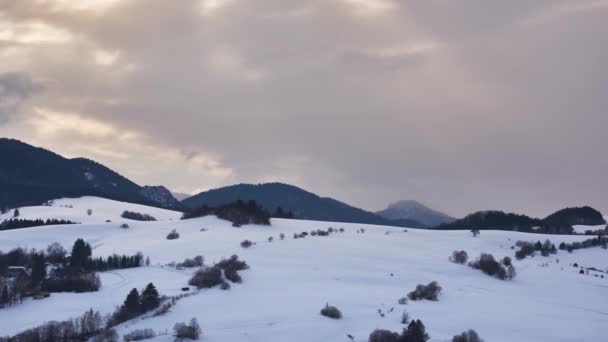De zonnestralen schijnen door de dichte wolken op het besneeuwde landschap — Stockvideo