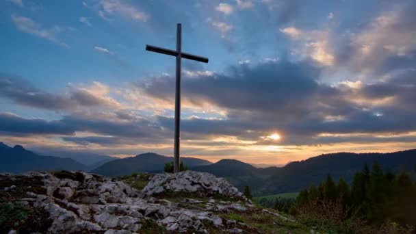 Keresztény kereszt egy sziklán Napnyugtakor, színes felhők, gyorsan mozgó felhők. 4K — Stock videók