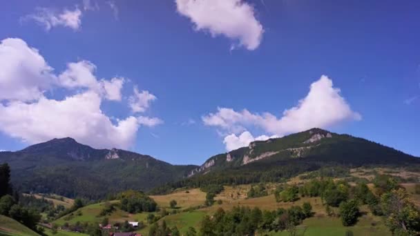 Karpat dağları köyün üzerinde yükseliyor. Mavi gökyüzünde hızlı hareket eden bulutlar. — Stok video