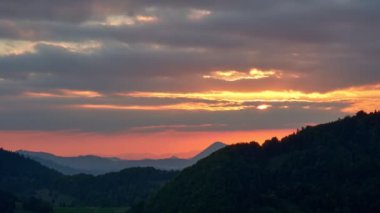 Bulutlu havada gün batımı, orman tepesi manzarası, 4K zaman dilimi. 