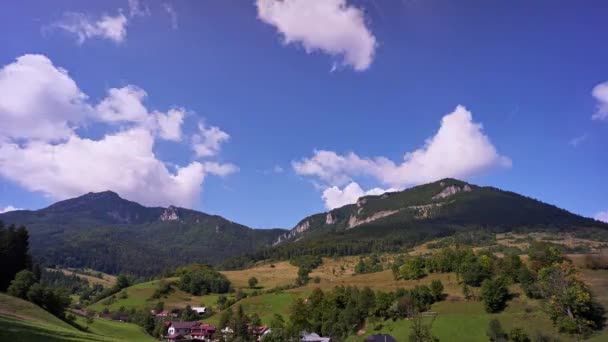 Карпатские горы возвышаются над деревней. Быстрые движущиеся облака в голубом небе. — стоковое видео