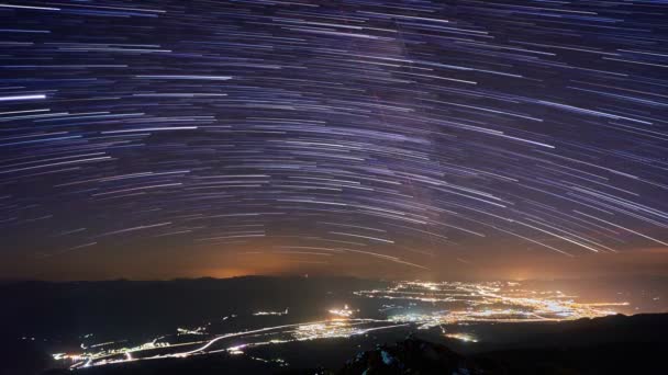 Star Trails In Night Sky. Verlichte nachtstad onder de sterren, — Stockvideo