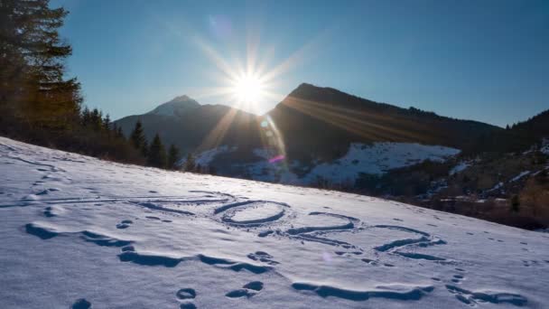 El sol se pone detrás de la montaña, cielo azul claro. Año 2022 escrito en la nieve. — Vídeos de Stock