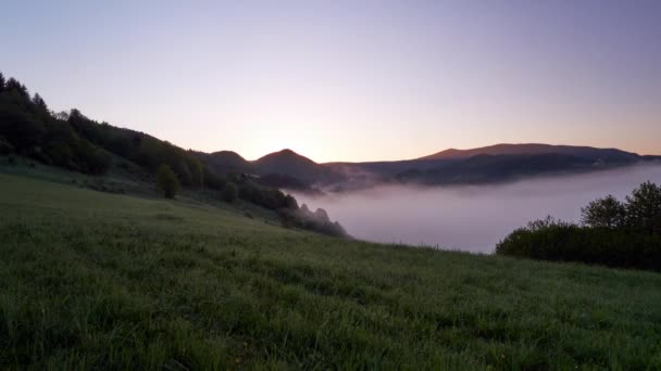 Die aufgehende Sonne flutet die neblige Berglandschaft mit hellem warmen Licht. Zeitraffer in 4K — Stockvideo