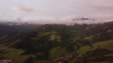 Clouds form over the forest hilly landscape shortly after the rain, at dusk in the golden hour. High quality 4k footage