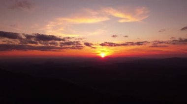 Dağ manzaralı destansı bir kayanın üzerinde gün batımına ait drone hava görüntüsüyle duran kişi. Yüksek kalite 4k görüntü