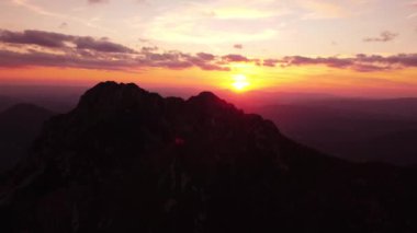 Kayalık bir dağın üzerinde güzel bir gün batımı. Dağın tepesinden uçuyor. 4 bin. Yüksek kalite 4k görüntü