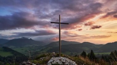 Gün batımında karlı bir kış manzarasında kayalık bir tepede çarpıcı bir haç. Tanrı 'yı, inancı, umudu, gücü ve kurtuluşu temsil ediyor. Bu video 4K zaman ayarlı. Dini etkinlikler ve terfiler için ideal.. 