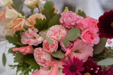 Temiz vazoları ve renkli çiçekleri olan beyaz masa örtüleri. Altın renkli tabaklar, peavh peçeteleri, masa numaraları ve ayna süslemeleri. Düğün günü..