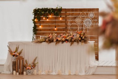 Romantik boho ana masası. Yeni evliler için bir ziyafette düğün dekoru. Kurumuş çiçekçi ve mumlar, boho tarzı. Gelin, damat ve misafirler için taşıma hizmeti.