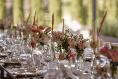 Çok güzel dekore edilmiş bir düğün masası randevusu. Baharın bahçesinde tabaklar ve peçetelerle süslenmiş güzel bir dekor. Düğün günü masada güzel çiçekler. Zarif yemek masası. Düğün günü.