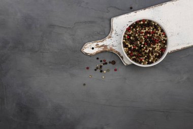 Üç çeşit biber, beyaz, siyah ve kırmızı gri taşlı arka planda beyaz bir kasede. Baharatlar