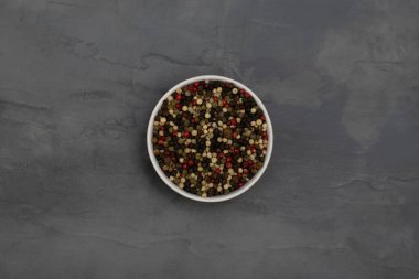 Üç çeşit biber, beyaz, siyah ve kırmızı gri taşlı arka planda beyaz bir kasede. Baharatlar