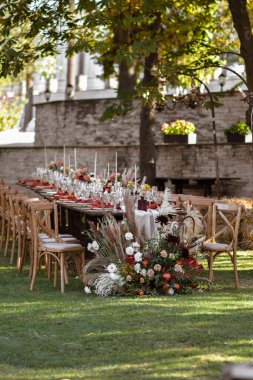 Çok güzel dekore edilmiş bir düğün masası randevusu. Baharın bahçesinde tabaklar ve peçetelerle süslenmiş güzel bir dekor. Düğün günü masada güzel çiçekler. Zarif yemek masası. Boho düğünü..