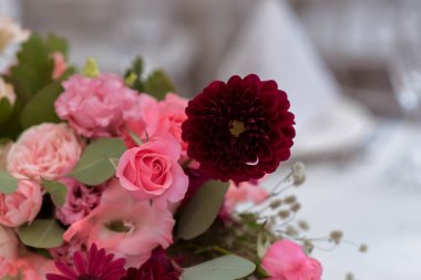 Temiz vazoları ve renkli çiçekleri olan beyaz masa örtüleri. Altın renkli tabaklar, peavh peçeteleri, masa numaraları ve ayna süslemeleri. Düğün günü..