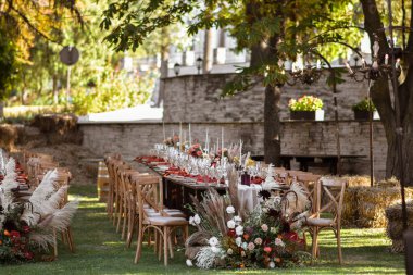 Çok güzel dekore edilmiş bir düğün masası randevusu. Baharın bahçesinde tabaklar ve peçetelerle süslenmiş güzel bir dekor. Düğün günü masada güzel çiçekler. Zarif yemek masası. Boho düğünü..