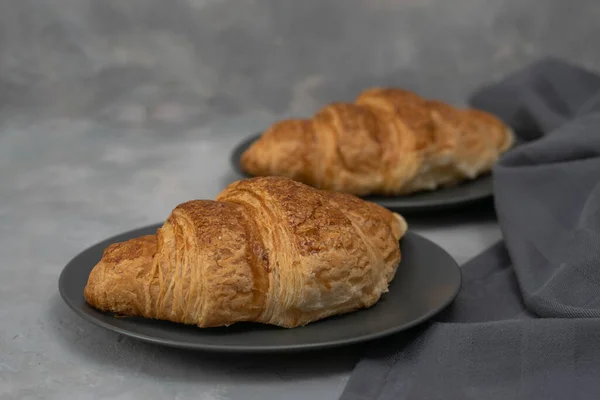Frisch gebackene hausgemachte Croissants zum Frühstück. Traditionelles Vollkorn-Croissant in einem grauen Teller auf Beton- oder Steingrund. — Stockfoto