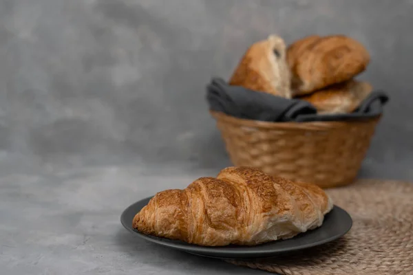 Croissants caseros recién horneados para el desayuno. Croissant tradicional y de grano entero en una placa gris sobre un fondo de hormigón o piedra. —  Fotos de Stock