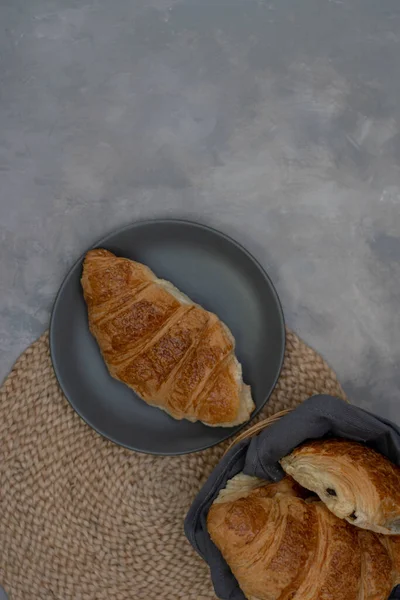 Freshly baked homemade croissants for breakfast. Traditional and whole-grain croissant in a gray plate on a concrete or stone background. — Stock Photo, Image