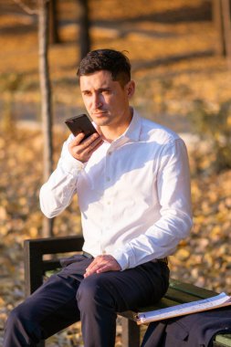 Genç ve başarılı iş adamı park yerinde duruyor ve telefonda konuşuyor. İş Portresi