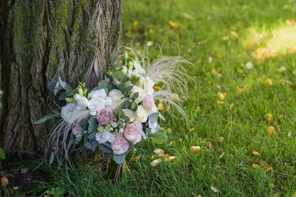 Ramo de novia moderno hecho de rosas, freesia, eustoma y eucalipto sobre hierba. — Foto de Stock