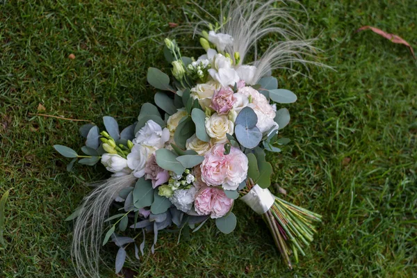 Modern bridal bouquet made from roses, freesia, eustoma and eucalyptus on grass. — 图库照片