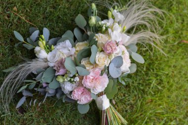 Çimlerin üzerinde gül, frezya, östoma ve okaliptüsten yapılmış modern gelin buketi. Düğün günü..