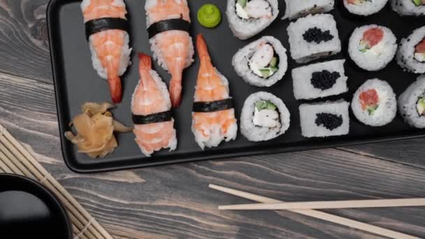 Japonské složení jídla. Různé druhy sushi umístěné na černé desce. — Stock video