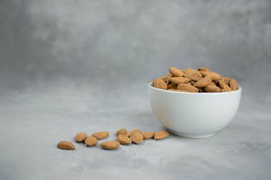 Badem, şam fıstığı ve kaju, açık gri bir zemin üzerinde keten peçetenin üzerindeki ahşap bir kaseye konur. Üst görünüm ve kopyalama alanı.