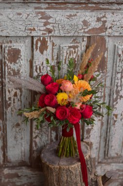 Düğün buketi. Gelinin buketi. Bir buket kırmızı ve sarı çiçek. Yıldız çiçeği ve güllerden oluşan bir gelin dueti. Düğün günü..