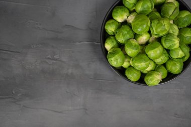 Gri arkaplanda taze Brüksel lahanası olan siyah kase..