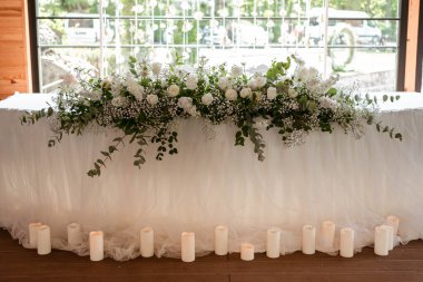 Güzel çiçeklerle dolu bir düğün resepsiyonunda ana masa. Düğün günü. Beyaz çiçekli düğün kimlikleri.