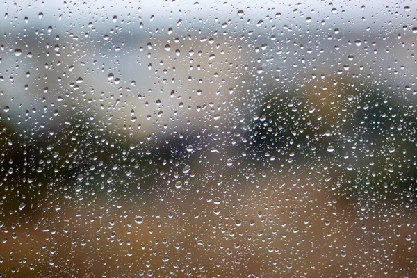 Camın üzerine renkli arka planda su damlacıkları. Su damlaları.