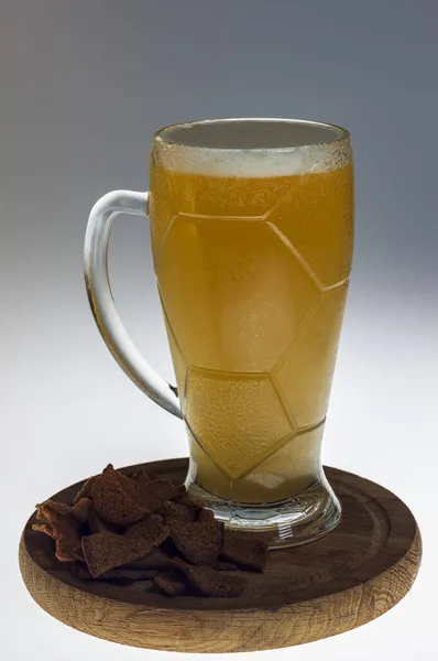 Bir bardak light bira ve beyaz bir masada tuzlanmış kızarmış ekmek kasesi. Beyaz arkaplan.