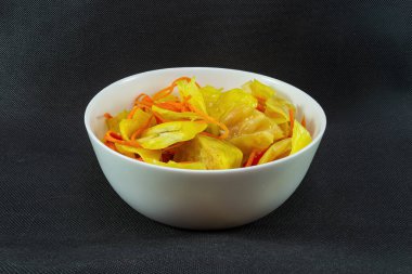 Körili lahana turşusu ve siyah arka planda bir tabak havuç.