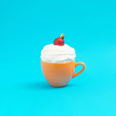 Krem şantili sarı kahve tuzuna kırmızı bir Noel süsü konuldu. Asgari fikir Xmas. Yeni Yıl 2022