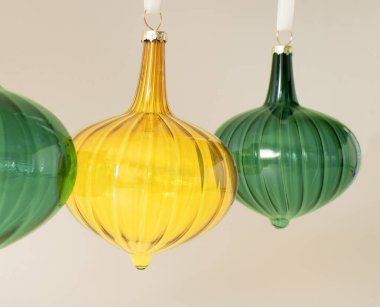 Pastel bej arkaplanının arkasındaki beyaz ipte parlak sarı ve yeşil renkte Noel tipi cam süsler asılı. Kış tatili ve yeni yıl kompozisyonu. Retro 80 ya da 90 'ların estetiği.