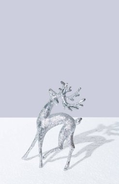 Gri arkaplana karşı beyaz kar üzerinde gümüş renkli ren geyiği. Minimum Noel ve Yeni Yıl Arifesi konsepti. Kış tatili yaratıcı planı.
