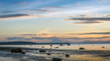 Beautiful Alaskan sunset on the Cook inlet with mountains and volcano in the background