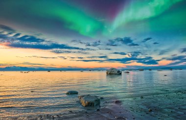 Şok edici güzellikte Alaska gün batımı aşçı koyunda Aurora Borealis bulutların ve dağların üzerinde beliriyor.
