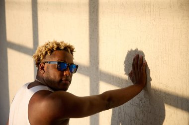 Güneş gözlüklü havalı siyah adam ve gölgesi duvarda
