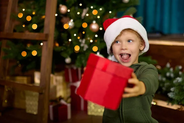 Niño Sombrero Navidad Está Sosteniendo Regalo Hermoso Paquete Sobre Fondo — Foto de Stock